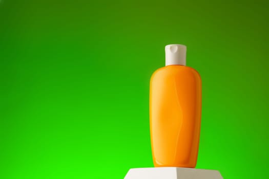 Cosmetic bottle with sunscreen lotion on green background