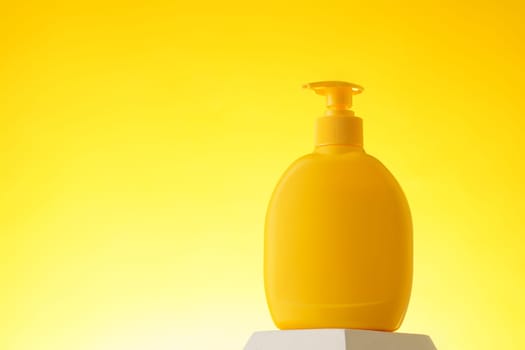 Cosmetic bottle with sunscreen lotion on yellow background