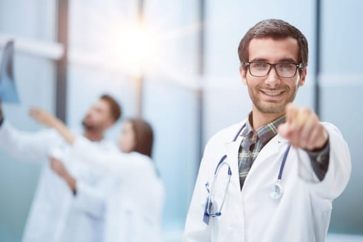 Young doctor man pointing with finger to the camera and to you, hand sign