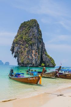 MAYA BAY, THAILAND - APRIL 14, 2014: Dramatic karst geography stands tall above traditional Thai longtail boats docked in the popular Maya Bay.