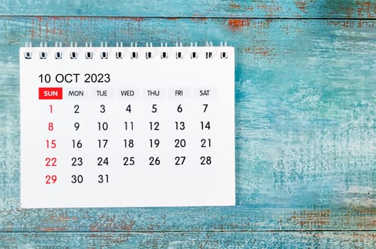 The October 2023 Monthly desk calendar for 2023 year on old blue wooden background.