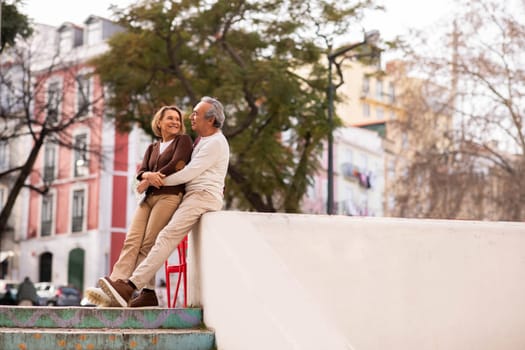 Romantic Senior Couple Sitting And Hugging In Urban Area Outdoor