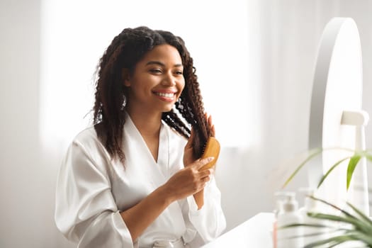 Smiling Young Black Woman Brushing Her Beautiful Hair With Comb At Home