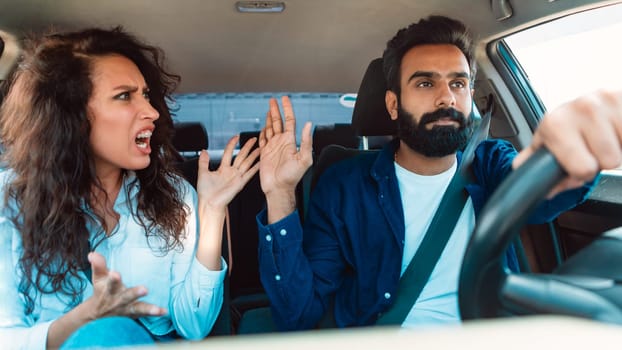 Emotional middle eastern couple having conflict in car, woman shouting at man, couple arguing about road