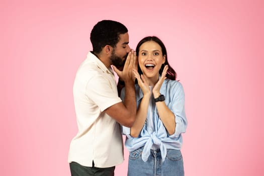 Middle eastern guy sharing secret with his excited pretty girlfriend