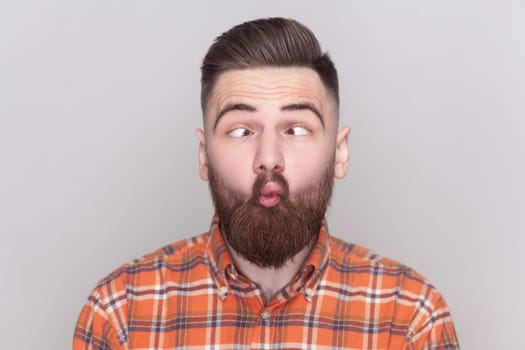 Funny crazy bearded man standing, crossed eyes with fish lips gesture, fool around, having fun.