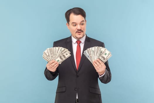 Rich man with mustache standing counting money., holding big fans of dollar banknotes.