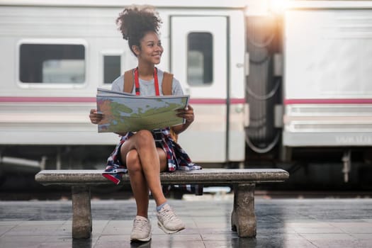 Young woman female smiling traveler with back pack looking to map while waiting for the train at train station. High quality photo