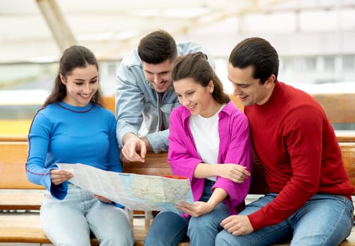 Two Couples Pointing At Map Choosing Vacation Destination At Airport