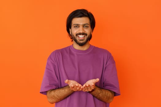 Happy smiling young indian man holding something in his palms