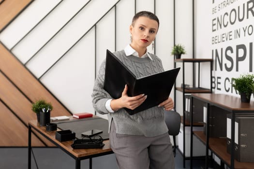 successful startup leader woman standing in the office holding a folder