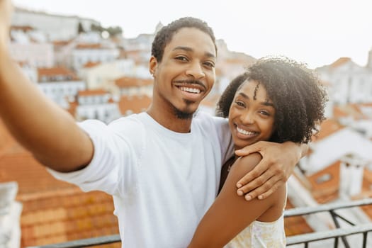 Smiling young african american guy hug lady in dress, taking selfie in city, enjoy date and travel, outdoor