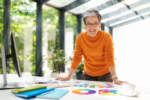 Cheerful mature woman designer working at office