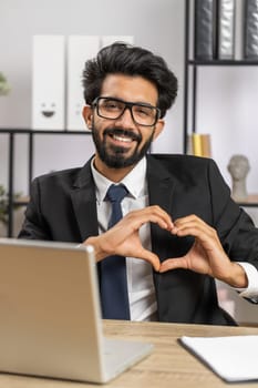 Indian business man makes symbol of love, showing heart sign to camera, express romantic feelings