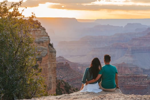 Happy couple on a steep cliff taking in the amazing view over famous Grand Canyon on a beautiful sunset, Grand Canyon National Park, Arizona, USA