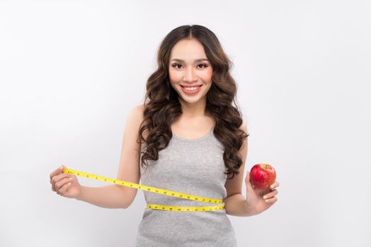 Woman measuring her waistline and holding apple. Weight losing concept.