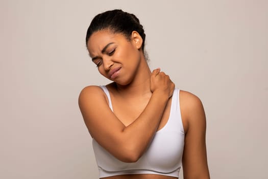 Young black woman suffering from pain, massaging neck