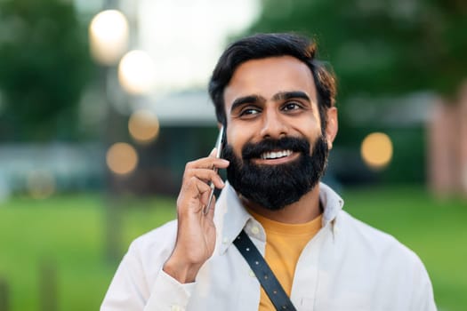 Young Indian Man Talking On Cellphone Walking In Urban Area
