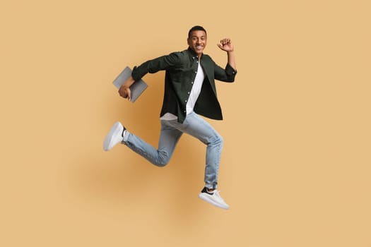 Excited young black guy independent contractor running with computer