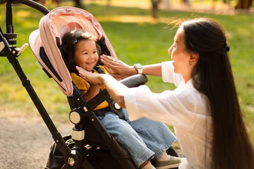 Korean Mommy With Baby Daughter In Stroller Playing At Park