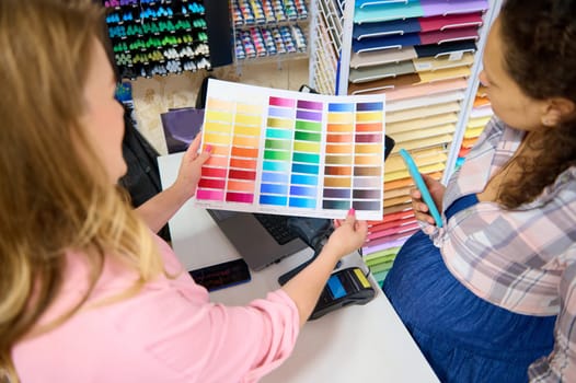 Focus on palette with color swatches of watercolor paints of various spectrums, in the hands of a saleswoman . Painting