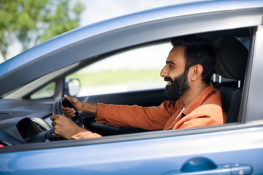 Profile portrait of smiling bearded arab man sitting in car
