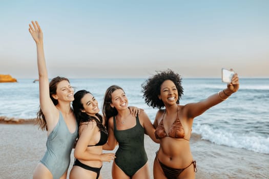 Excited carefree multiracial ladies friends capturing moments spending time together at the beach