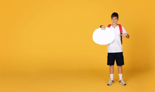 Glad caucasian teenage boy pupil point finger to abstract cloud for ad and offer with free space
