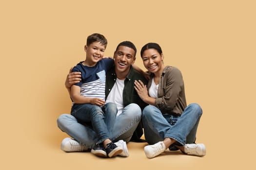 Happy cute family parents and son posing on colored background