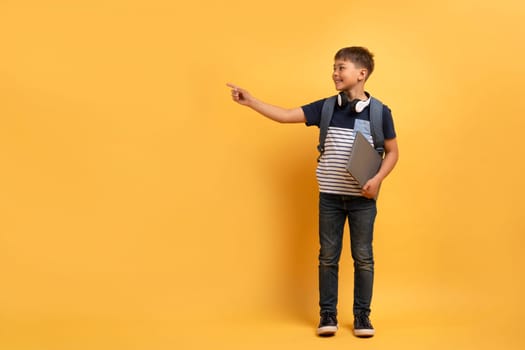 Cute schoolboy showing pointing at copy space and smiling