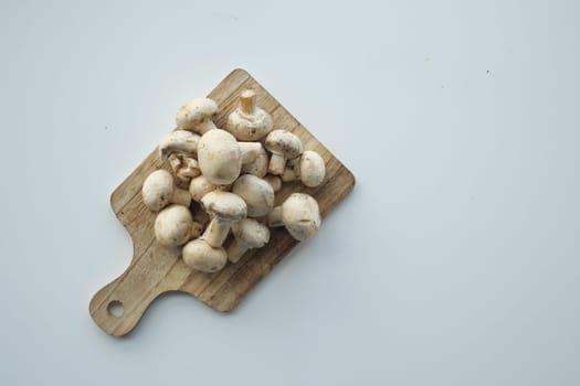 Fresh champignons mushroom on a chopping board on white background