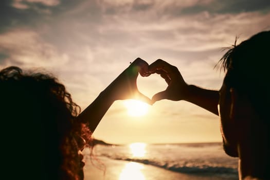 People with heart hands, sunset on beach, silhouette with love and romance sign, travel and outdoor. Adventure, emoji and care with health in nature, support and commitment, couple with trust and sea.