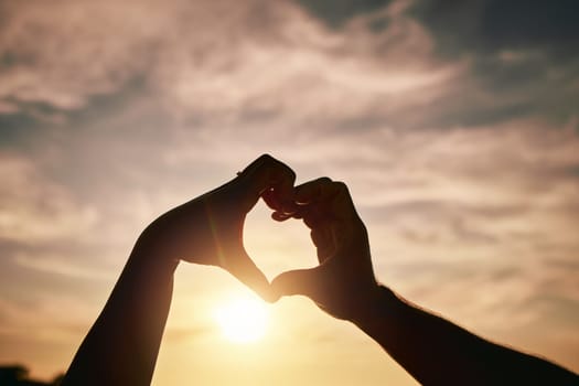 Heart hands, sunset on beach and silhouette with love and romance sign, people travel and outdoor. Adventure, emoji and care with health in nature, support and commitment, couple with trust and sea.
