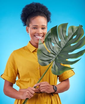 Fashion, portrait and black woman with plant on blue background for eco friendly, organic and natural clothes. Nature, happy and female person with monstera leaf for sustainable clothing in studio