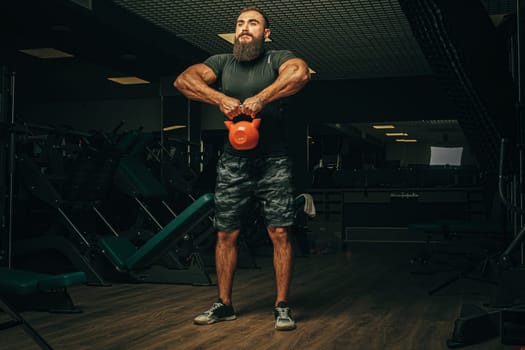 Bodybuilder doing exercises with dumbbells in a dark gym