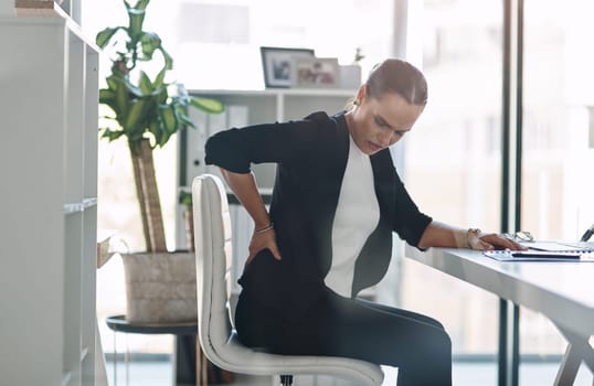 These long hours are starting to negatively affect her health. Cropped shot of an attractive young businesswoman suffering from back pain while working inside her office.