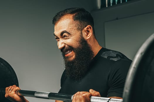 Muscular man in black sportswear lifting barbell in a gym