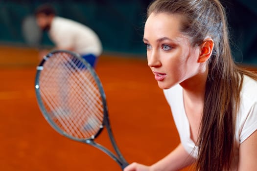 Attractive woman tennis player waiting for service at indoor court