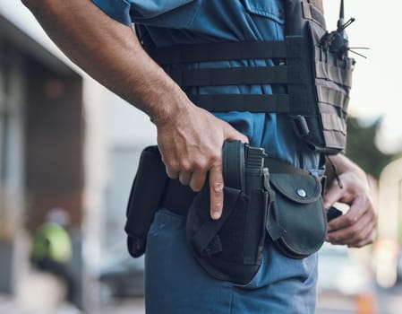 Security, police and hands of man with gun in city for shift, inspection and supervision on patrol. Weapon, law enforcement and closeup of male person in town for safety, crime and protection service