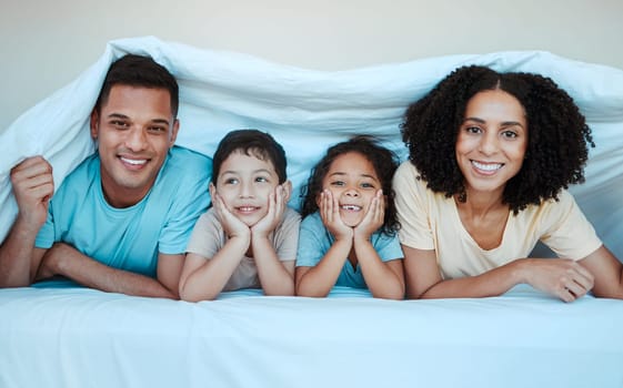 Blanket, bed and portrait of parents with children for bonding, quality time and affection in morning. Love, family and happy mother, father and kids laying in bedroom for fun, playful and relaxing