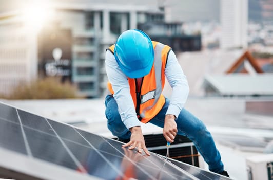 Engineer man, screwdriver and solar panel on roof for maintenance, industry and construction in city. Technician, tools and photovoltaic system with helmet, development and renewable energy in cbd