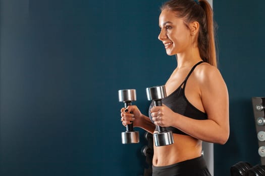 Young sporty woman training with dumbbells. Sport and bodybuilding concept