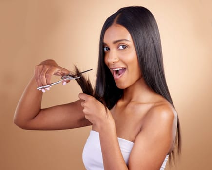 Surprise, cut and portrait of Indian woman with scissors in studio for diy, haircut or styling on brown background. Wow, face and female model with hair, treatment or styling results with beauty tool