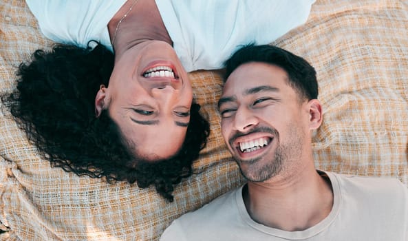 Face, picnic and smile with a couple laughing on a blanket from above, lying on the ground while on a date. Love, happy or funny with a man and woman bonding together for romance on valentines day