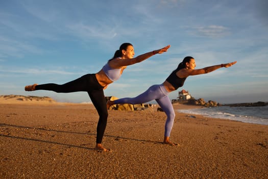 Happy slim millennial caucasian twins sisters women do exercises balance, practice yoga, asana