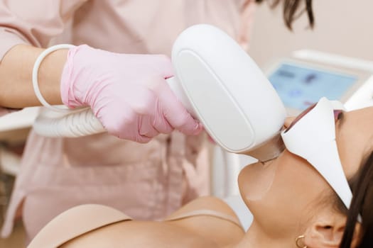 Elos epilation hair removal procedure on the face of a woman. Beautician doing laser rejuvenation in a beauty salon. Facial skin care. Hardware ipl cosmetology. Laser mustache hair removal