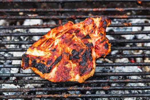 Close up of pork steak grilled on a charcoal barbeque isolated.