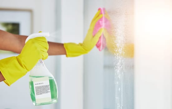 Window, spray and hands cleaning in a home for hygiene, germ protection and maintenance with a chemical in a house. Bacteria, glass and housekeeper or cleaner working on a wood desk with gloves