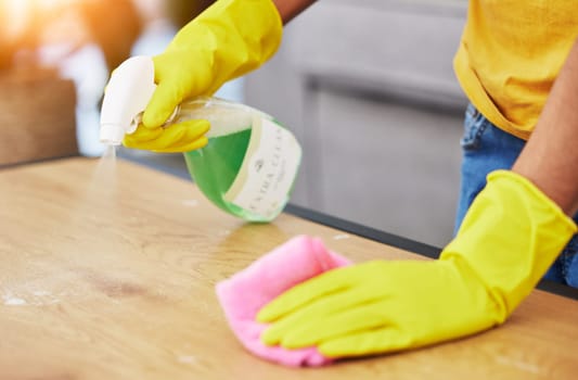 Table, spray and hands cleaning in a home for hygiene, germ protection and maintenance with a chemical in a house. Bacteria, service and housekeeper or cleaner working on a wood desk with gloves