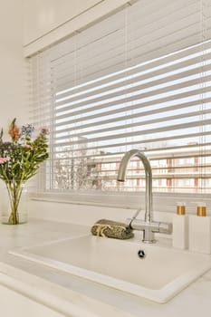 a kitchen sink with a window with white blinds